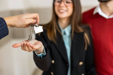 Ev anahtarlığının ve anahtarlığın yakın plan çekimi emlakçıdan yeni ev sahiplerine devrediliyor. Gayrimenkul, ipotek ve taşınma kavramları için ideal.