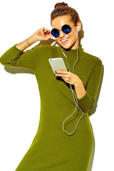 Portrait of beautiful happy cute smiling brunette woman girl in casual blue hipster summer clothes with no makeup isolated on white in sunglasses listening music in smartphone with headphones — Stock Photo, Image