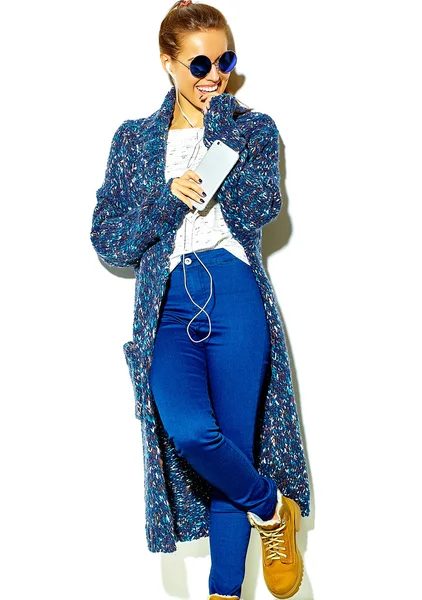 Portret van mooi gelukkig schattige lachende brunette vrouw meisje in casual blauwe hipster zomer kleding zonder make-up geïsoleerd op wit in zonnebril luisteren van muziek in smartphone met koptelefoon vinger bijten — Stockfoto