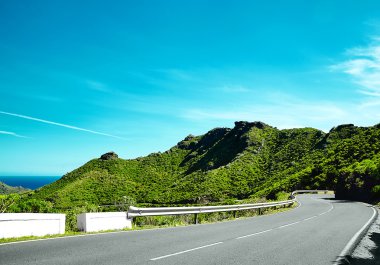 Asfalt yol ile dağların ve mavi gökyüzünün güzel görünümü mavi fiyort ve yosun dağları arasında kıvrımlı.