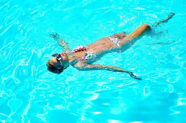 Foto de moda de sexy modelo de chica hermosa caliente con el pelo oscuro en traje de baño de colores nadando en la espalda en la piscina —  Fotos de Stock