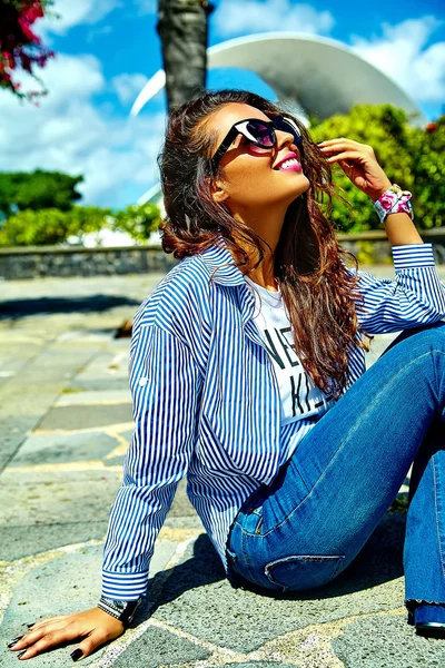 Mode stijlvolle mooie jonge lachende brunette vrouw model in zomer hipster casual blauwe kleren poseren in de straat — Stockfoto