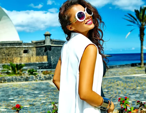 Portrait of beautiful smiling sexy brunette businesswoman model in white clothes in sunglasses posing behind blue sky — Stock Photo, Image