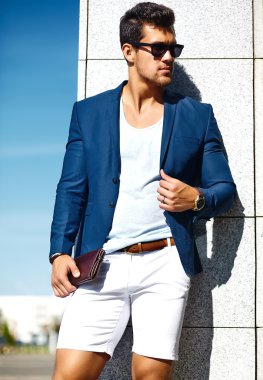 Yüksek moda bakmak. Genç şık emin mutlu yakışıklı işadamı model adam gökyüzü arkasında güneş gözlüğü sokakta mavi takım elbiseli