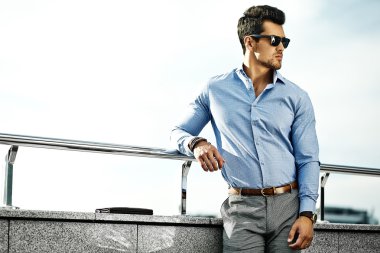 Fashion portrait of young sexy handsome model man in casual cloth in sunglasses in the street