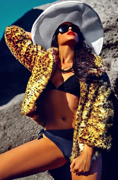 Alta moda look.glamor sexy banhado a sol branco modelo menina em casaco de pele de leopardo posando ao ar livre em estilo moda e grande chapéu branco — Fotografia de Stock