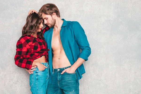 性感漂亮的女人和她英俊的男朋友模特们穿着牛仔裤衣服站在灰墙边 年轻夫妇在做爱前拥抱 性感的一对越来越接近亲吻 情人夫妇 — 图库照片