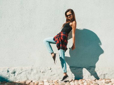 Güzel gülümseyen modelin portresi. Hipster desenli gömlek ve kot pantolon giymiş bir kadın. O, sokakta duvarın yanında poz veriyor. Komik ve pozitif kadın dışarıda eğleniyor ve yürüyor.