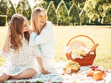 İki güzel, güler yüzlü yeniyetme yaz elbisesi ve şapkası içinde iki genç bayan. Dışarıda piknik yapan kaygısız kadınlar. Çimlerin üzerinde oturan, kitap okuyan, meyve ve peynir yiyen pozitif modeller.