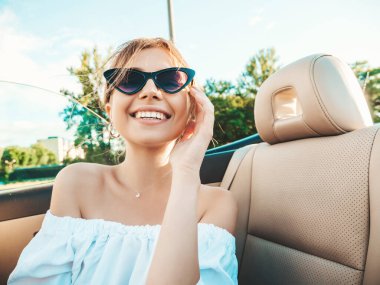 Üstü açık arabadaki güzel ve gülümseyen yeniyetme kadın portresi. Cabriolet kullanan kaygısız seksi kadın. Gün batımında güneş gözlüğüyle gezmek ve eğlenmek