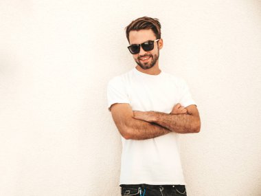Yakışıklı, gülümseyen stil sahibi Lambersex modelinin portresi. Beyaz tişört giyen adam. Sokakta güneş gözlükleriyle poz veren modacı erkek.