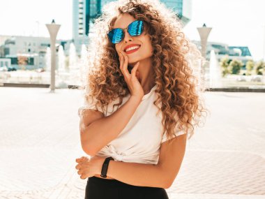 Kıvırcık saçlı, yaz hippi kıyafetleri giymiş güzel bir mankenin portresi. Sokakta poz veren tasasız bir model. Modayı takip eden eğlenceli ve olumlu kadın.