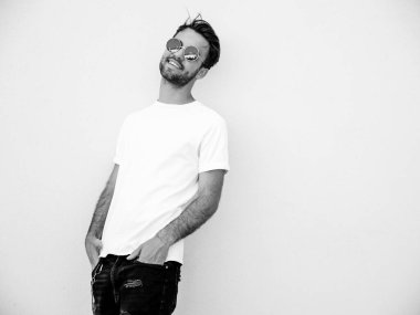 Yakışıklı, kendine güvenen, stil sahibi, Lambersex mankeni portresi. Beyaz tişört giyen adam. Moda erkek, dışarıda güneş gözlüklü, duvarın yanında poz veriyor.