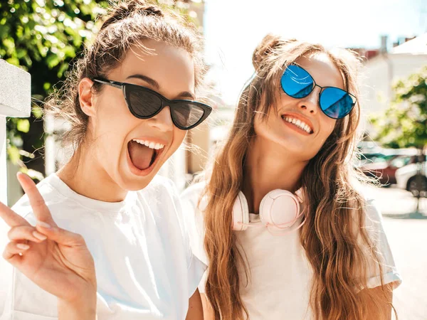 两个年轻美丽的嬉皮士女性穿着时髦的夏季白色T恤衫的肖像 性感无忧无虑的女性在街上摆出背景 拥抱和发疯的正面模特 — 图库照片