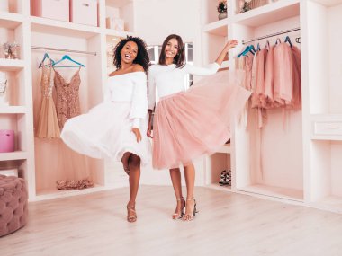 Son moda yaz elbiseleri içinde gülümseyen iki güzel uluslararası hippi kadın. Pembe gardıropta poz veren kaygısız seksi kadınlar. Pozitif modeller eğleniyor. Arkadaşlık kavramı 