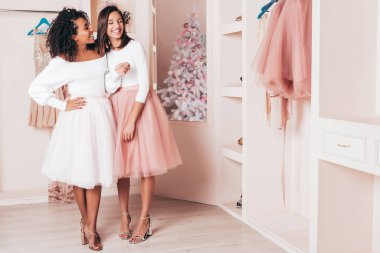 Son moda yaz elbiseleri içinde gülümseyen iki güzel uluslararası hippi kadın. Pembe gardıropta poz veren kaygısız seksi kadınlar. Pozitif modeller eğleniyor. Arkadaşlık kavramı 