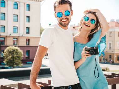 Gülümseyen güzel bir kadın ve yakışıklı erkek arkadaşının portresi. Günlük kot pantolon giymiş bir kadın. Neşeli bir aile. Kadın eğleniyor. Arka planda ellerinde kamerayla poz veren çift.