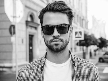 Yakışıklı, gülümseyen stil sahibi Lambersex modelinin portresi. Beyaz tişört giyen adam. Moda erkeği güneş gözlükleriyle sokakta poz veriyor. 