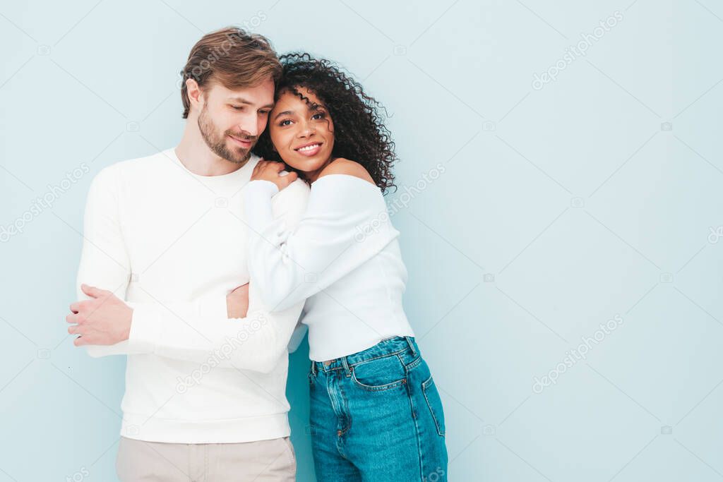 Smiling beautiful woman and her handsome boyfriend. Happy cheerful multiracial family having tender moments on grey background  in studio. Multiethnic models hugging. Embracing each other.Love concept