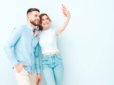 Gülümseyen güzel kadın ve yakışıklı erkek arkadaşı. Mutlu mutlu aile stüdyoda açık mavi duvarın yanında hassas anlar yaşıyor. Saf modeller kucaklaşıyor. Birbirlerine sarılıyorlar. Aşk kavramı.