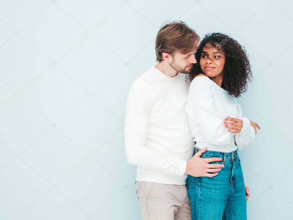 Smiling beautiful woman and her handsome boyfriend. Happy cheerful multiracial family having tender moments on grey background  in studio. Multiethnic models hugging. Embracing each other.Love concept