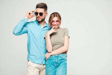 Gülümseyen güzel kadın ve yakışıklı erkek arkadaşı. Mutlu, neşeli bir aile, hassas anlar yaşıyor. Stüdyoda gri arka planda poz veriyor. Saf modeller, güneş gözlükleriyle sarılıyor.