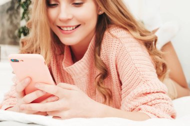 Gündelik giysiler içinde genç ve güzel bir kadın. Seksi kaygısız kadın sabahları lüks bir dairede ya da beyaz iç mekanda otel odasında yatar. Akıllı telefon ekranına bakan ateşli model, uygulamalar kullanıyor