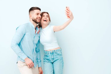 Gülümseyen güzel kadın ve yakışıklı erkek arkadaşı. Mutlu mutlu aile stüdyoda açık mavi duvarın yanında hassas anlar yaşıyor. Saf, neşeli modeller sarılıyor. Birbirlerine sarılıyorlar.