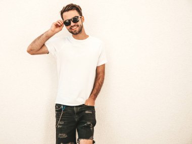 Yakışıklı, gülümseyen stil sahibi Lambersex modelinin portresi. Beyaz tişört giyen adam. Moda erkeği güneş gözlükleriyle sokakta poz veriyor. 