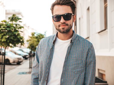 Yakışıklı, gülümseyen stil sahibi Lambersex modelinin portresi. Beyaz tişört giyen adam. Moda erkeği güneş gözlükleriyle sokakta poz veriyor. 