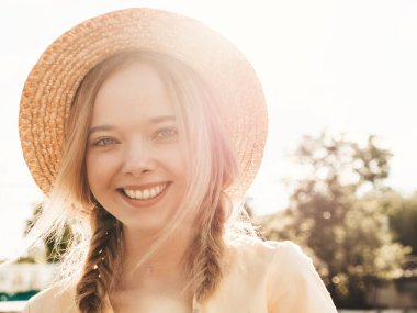 Moda bir yaz elbisesi içinde gülümseyen hippi bir kadının portresi. Günbatımında şapkayla sokakta poz veren kaygısız seksi kadın. Toprak döşeme üzerinde pozitif model