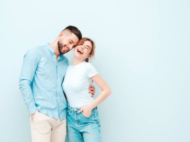 Gülümseyen güzel kadın ve yakışıklı erkek arkadaşı. Mutlu mutlu aile stüdyoda açık mavi duvarın yanında hassas anlar yaşıyor. Saf, neşeli modeller sarılıyor.