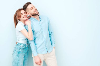 Gülümseyen güzel kadın ve yakışıklı erkek arkadaşı. Mutlu mutlu aile stüdyoda açık mavi duvarın yanında hassas anlar yaşıyor. Saf, neşeli modeller sarılıyor.