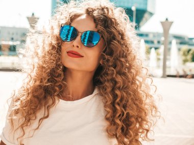 Kıvırcık saçlı, yaz hippi kıyafetleri giymiş güzel bir mankenin portresi. Sokakta poz veren tasasız bir model. Modayı takip eden eğlenceli ve olumlu kadın.