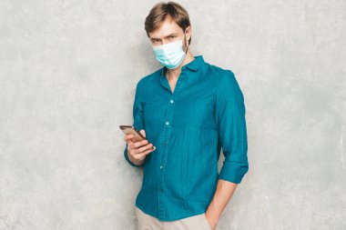 Yakışıklı, güler yüzlü hippi, keresteci iş adamı mankeni, günlük kot gömlek giyiyor. Moda adamı stüdyoda duvarın yanında poz veriyor. Cep telefonu ekranına bakıyor, uygulamalar kullanıyor. Koruyucu maskeyle