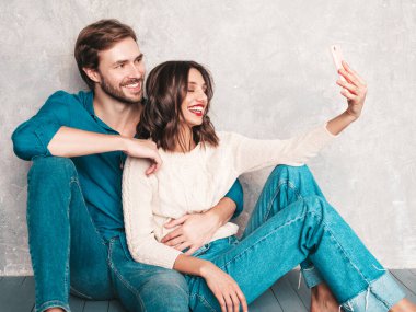 Gülümseyen güzel kadın ve yakışıklı erkek arkadaşı. Mutlu mutlu aile stüdyoda gri duvarın yanında hassas anlar yaşıyor. Saf, neşeli modeller sarılıyor. Birbirlerine sarılıyorlar.