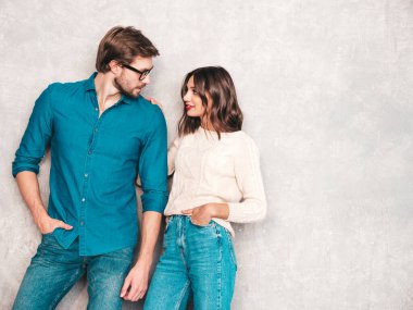 Gülümseyen güzel kadın ve yakışıklı erkek arkadaşı. Mutlu mutlu aile stüdyoda gri duvarın yanında hassas anlar yaşıyor. Saf, neşeli mankenler sarılıyor.