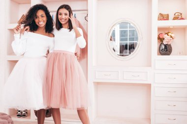 Son moda yaz elbiseleri içinde gülümseyen iki güzel uluslararası hippi kadın. Pembe gardıropta poz veren kaygısız seksi kadınlar. Pozitif modeller eğleniyor. Arkadaşlık kavramı 