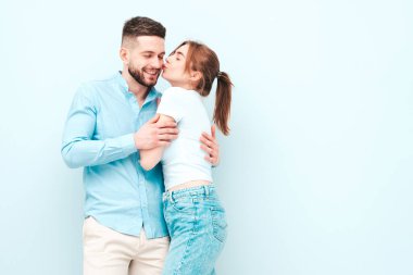 Gülümseyen güzel kadın ve yakışıklı erkek arkadaşı. Mutlu mutlu aile stüdyoda açık mavi duvarın yanında hassas anlar yaşıyor. Saf, neşeli modeller sarılıyor.