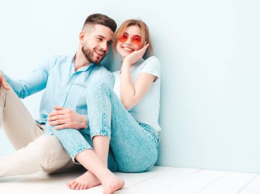 Gülümseyen güzel kadın ve yakışıklı erkek arkadaşı. Mutlu mutlu aile stüdyoda açık mavi duvarın yanında hassas anlar yaşıyor. Saf, neşeli modeller sarılıyor.