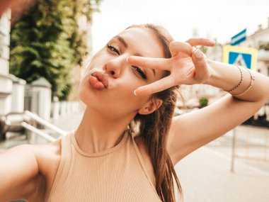 Hipster kot pantolon giymiş güzel gülümseyen bir mankenin portresi. Sokakta poz veren modaya uygun bir kadın. Komik ve pozitif kadın güneş gözlükleriyle eğleniyor. Selfie çekiyoruz.