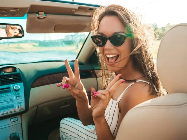Üstü açık arabadaki güzel ve gülümseyen yeniyetme kadın portresi. Cabriolet kullanan kaygısız seksi kadın. Gün batımında güneş gözlüğüyle gezmek ve eğlenmek