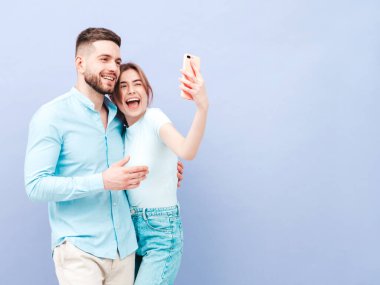 Gülümseyen güzel kadın ve yakışıklı erkek arkadaşı. Mutlu mutlu aile stüdyoda mor duvarın yanında hassas anlar yaşıyor. Saf, neşeli modeller sarılıyor. Selfie çekiyoruz.