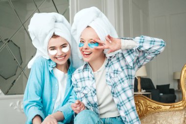 Gözlerinin altında bantlarla gülümseyen iki güzel kadın. Lüks bir dairede ya da otel odasında yatakta oturan kaygısız seksi mankenler. Evde kafalarına havlu geçirip güzellik tedavisi yapıyorlar.