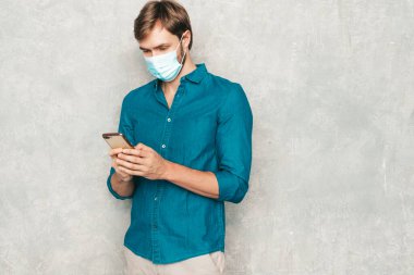 Yakışıklı, güler yüzlü hippi, keresteci iş adamı mankeni, günlük kot gömlek giyiyor. Moda adamı stüdyoda duvarın yanında poz veriyor. Cep telefonu ekranına bakıyor, uygulamalar kullanıyor. Koruyucu maskeyle