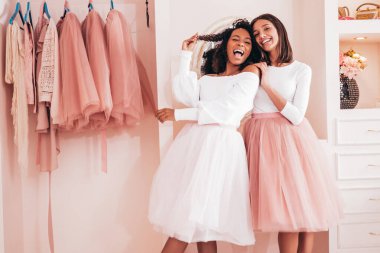 Son moda yaz elbiseleri içinde gülümseyen iki güzel uluslararası hippi kadın. Pembe gardıropta poz veren kaygısız seksi kadınlar. Pozitif modeller eğleniyor. Arkadaşlık kavramı 