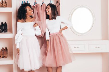 Son moda yaz elbiseleri içinde gülümseyen iki güzel uluslararası hippi kadın. Pembe gardıropta poz veren kaygısız seksi kadınlar. Pozitif modeller eğleniyor. Arkadaşlık kavramı 