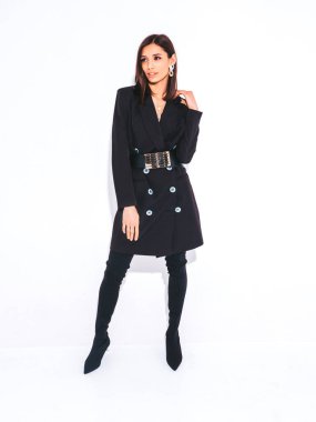 Güzel, güler yüzlü, güzel, siyah iş elbisesi içinde esmer bir kadın. Stüdyoda gri arka planda poz veren kaygısız bir kadın. Parlak akşam makyajlı, şık bir model.