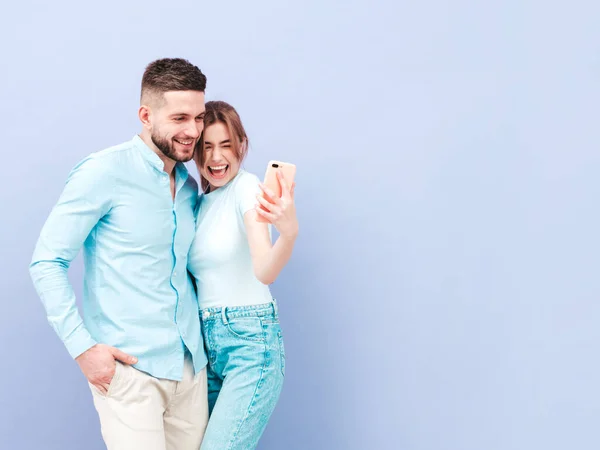 Smiling beautiful woman and her handsome boyfriend. Happy cheerful family having tender moments near purple wall in studio.Pure cheerful models hugging.Embracing each other.Taking selfie