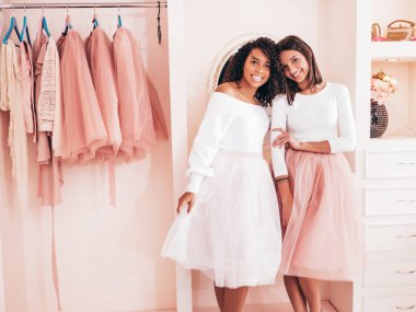 Son moda yaz elbiseleri içinde gülümseyen iki güzel uluslararası hippi kadın. Pembe gardıropta poz veren kaygısız seksi kadınlar. Pozitif modeller eğleniyor. Arkadaşlık kavramı 